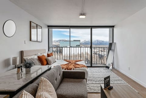 Wake up to sweeping mountain views from this bright studio featuring a cozy bed, sofa, and large windows 🌄🛋️✨
