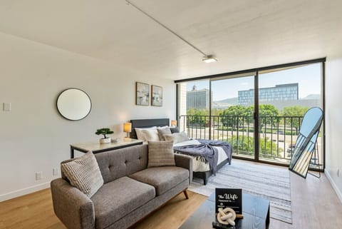 Bright living area w/ comfy sofa, TV & sliding doors opening to a balcony w/ city views