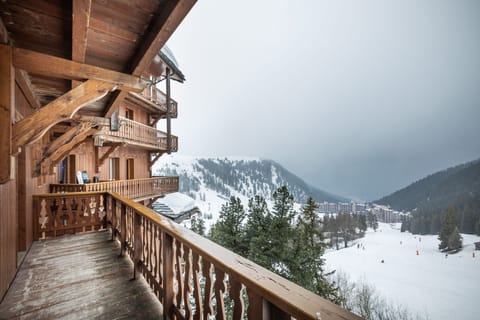 Take in the serene mountain views and fresh alpine air from this cosy wooden balcony, a peaceful escape surrounded by snowy peaks.