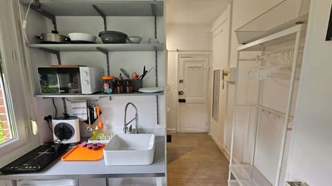 Kitchenette ouverte sur l'espace chambre, équipée avec plaque de cuisson, machine à café, micro-ondes et petit réfrigérateur.