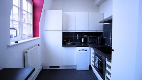 Cuisine équipée avec réfrigérateur avec freezer, lave-vaisselle, micro-ondes, machine à café, bouilloire, plaques de cuisson et four.