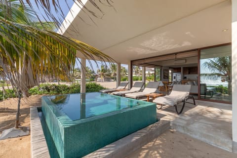 Enjoy direct beach access from this luxurious villa, featuring a private plunge pool, sun loungers, and a shaded lounge area.