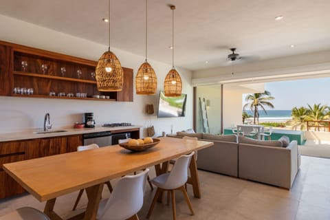 A spacious open-concept kitchen and dining area with modern lighting and natural wood finishes, perfect for entertaining and shared meals.