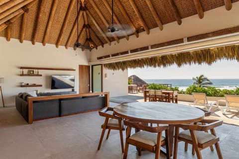 Enjoy open-air dining under a thatched roof with stunning ocean views, perfect for meals with family and friends.