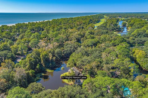 Aerial view of 57 Night Heron Lane, nestled among lush Lowcountry trees with serene lagoon views and just steps from the beach in Sea Pines.
