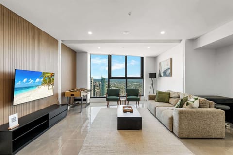 Stylish living room featuring a custom timber look TV wall, smart TV, modern armchairs, and even a foosball table for fun. All happening next to the broad Ocean views.