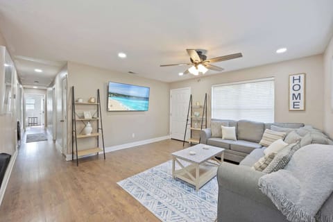 Cozy living room with a sectional sofa, wall-mounted TV, and natural light from a large window.