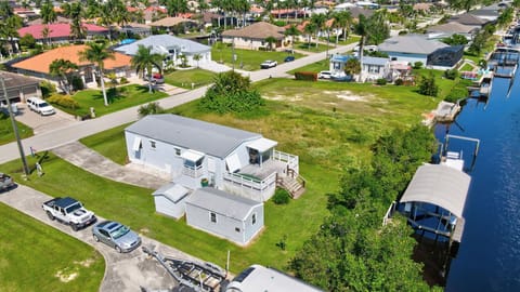 An aerial view of the home showcasing the driveway, back deck and boat lift and dock 