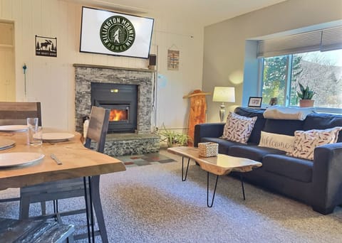 Relax in this warm open-concept space featuring a live-edge dining table and a stone fireplace for cozy mountain evenings.