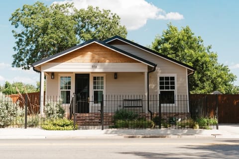 Exterior of the Gloria Cottage in a fully fenced yard. The driveway is not fenced.