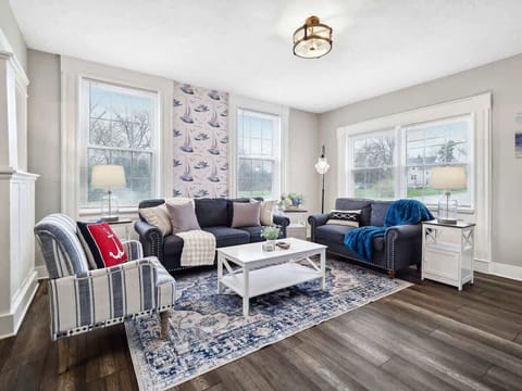 Bright living room w/ cozy seating, blue accents & large windows letting in natural light