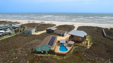 Aerial view of the beachfront compound with guitar-shaped pool, three units, and direct beach access