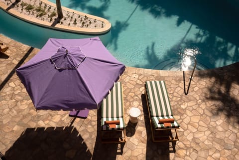 Enjoy the sun-drenched poolside with comfortable loungers and a refreshing dip, perfect for unwinding in a tranquil, tropical setting.