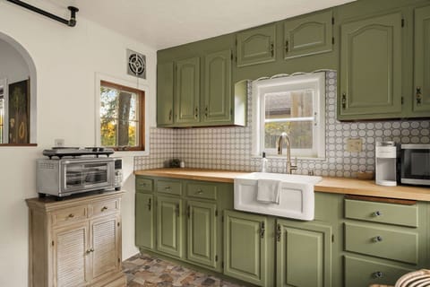 - Whip up meals in this charming, fully stocked kitchen with vintage flair
- Includes microwave, Keurig, toaster oven, and stove for all your needs
- Gorgeous green cabinets and tile work add personality and warmth