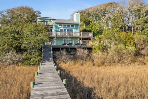 Waterfront property nestled among mature trees with private boardwalk access through natural marshlands.