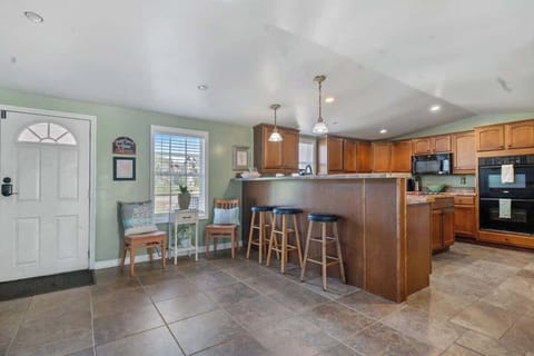 Welcome to the open entryway leading to the spacious kitchen, complete with bar stools, seating, and tiled floors as you step inside.