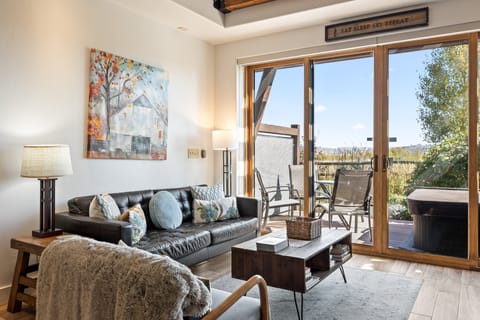- Inviting living room with stylish leather sofa  
- Artwork and décor create a welcoming retreat  
- Sliding doors open to patio and hot tub views