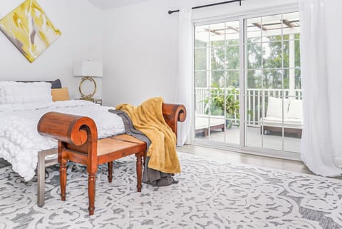 Cozy bedroom features soft white bedding a warm mustard throw and a wooden bench