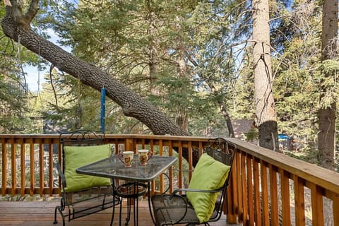 A spacious wooden deck on the back of the house offers a serene spot for morning coffee or evening relaxation, with views of the dense, green canopy and glimpses of the nearby mountains.