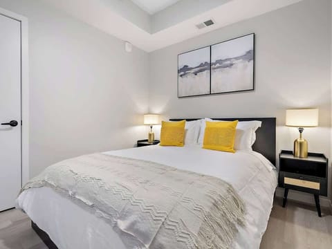 Serene bedroom with plush bedding, bright yellow accents, and warm bedside lighting.