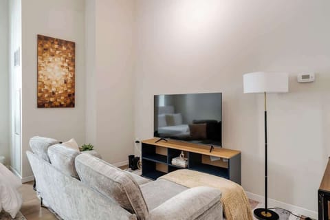 Relax in this cozy living space with a plush sofa, smart TV, and modern decor.