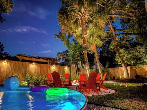 Oasis-style backyard with ambient lighting, fire pit, and cowboy tank pool to hang out with friends and family