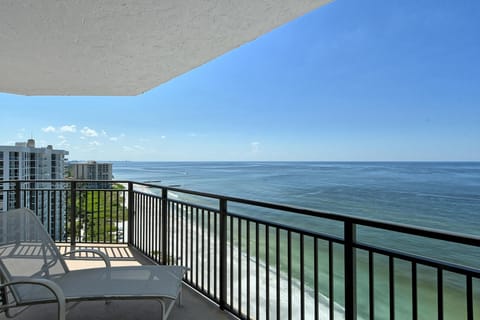 Balcony with metal railing and lounge chairs overlooking the beach and expansive ocean views.