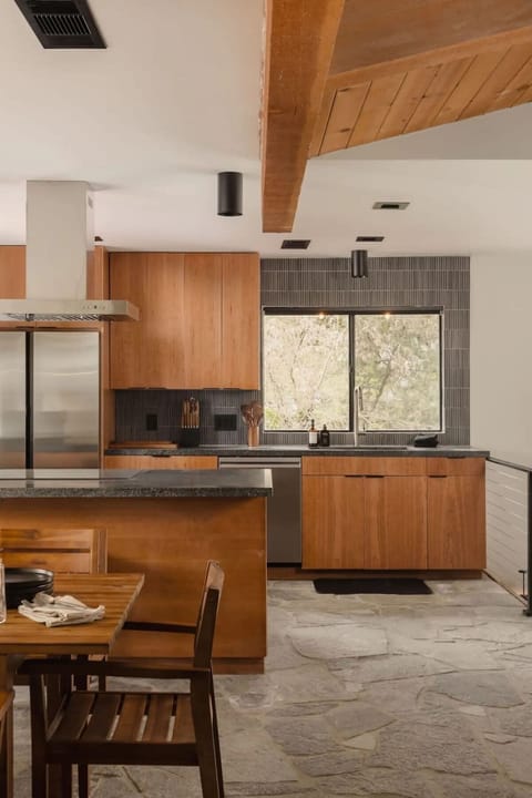 The open layout of the kitchen flows seamlessly into the dining area where a wooden table, with seating for eight, creates an inviting space for shared meals.