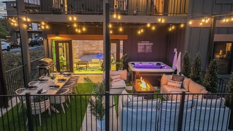 Outdoor patio with dining area, fire pit, and hot tub under string lights