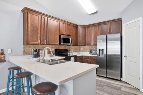 Modern kitchen with warm cabinetry, stainless steel appliances, and a breakfast bar—perfect for cooking and casual dining