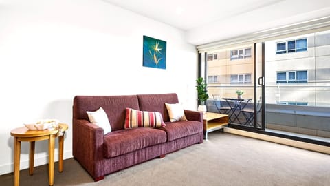 A welcoming living area with a deep maroon sofa opening directly to the balcony.