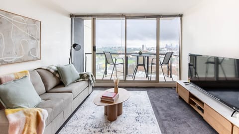 Bright living room with floor to ceiling windows and sweeping city view