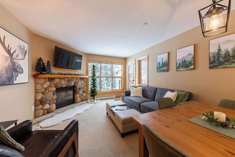 Spacious open living area with gas fireplace and forest views