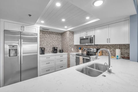 Modern kitchen view w/ stainless steel appliances, mosaic backsplash & ample prep space.