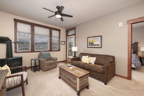 Relax in this cozy living room with leather sofa, mountain views, and rustic touches that create the perfect mountain retreat atmosphere.