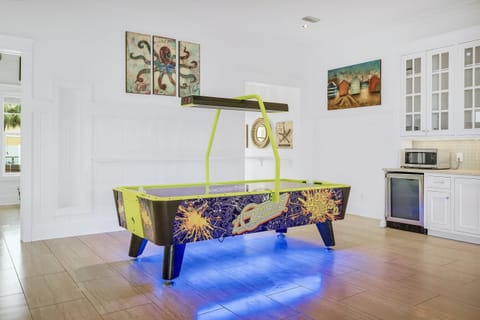 1st Floor - Game room with air hockey, custom arcades, 4K Smart TV, dining table, and a wet bar complete with mini fridge, ice maker, sink, and microwave