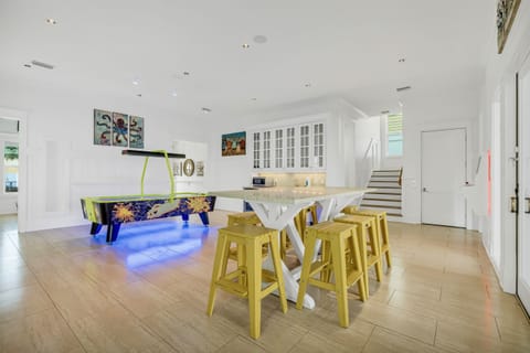 1st Floor - Game room with air hockey, custom arcades, 4K Smart TV, dining table, and a wet bar complete with mini fridge, ice maker, sink, and microwave