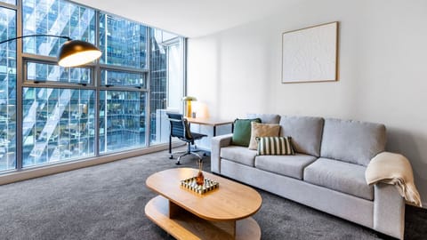 Sun streams through expansive floor-to-ceiling windows into a beautifully styled, light-filled living room.