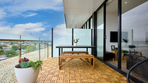 Host unforgettable gatherings on this expansive balcony featuring stylish timber decking and vast open-sky views.