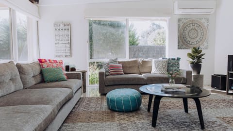 This massive, welcoming living room features dual plush sofas and a playful pop of color from a textured turquoise ottoman.
