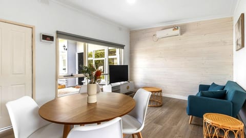 This inviting living and dining space pairs coastal charm with a comfortable, sunlit open layout.