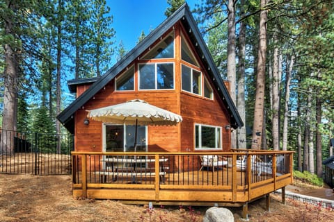 A charming wooden A-frame cabin nestled among towering pine trees, featuring a spacious deck and forest setting perfect for mountain getaways.