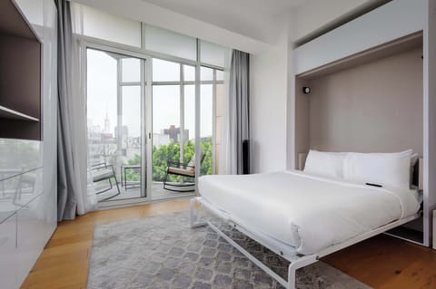 Bright and modern bedroom with floor-to-ceiling windows and relaxing city views.
