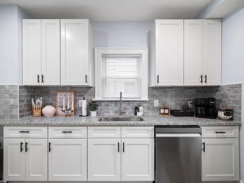 Sleek kitchen w/ white cabinetry, stainless appliances & ample counter space