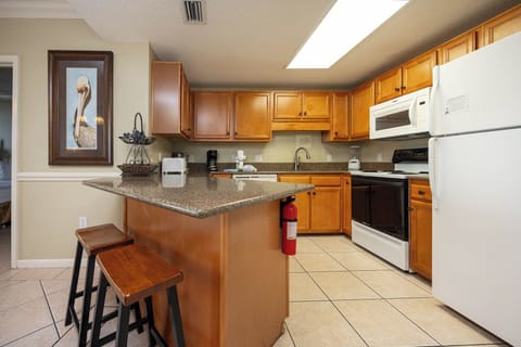 Prepare meals in this inviting kitchen featuring wood cabinetry, a breakfast bar, and white appliances