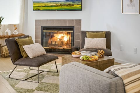Cozy living room with sofa, chairs, board games, 50" Smart TV, and a fireplace.