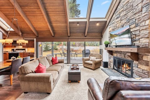 Living Room: Couch, 2 chairs, 55” TV w/cable, sound bar, gas fireplace, vaulted ceilings, skylights, open layout
