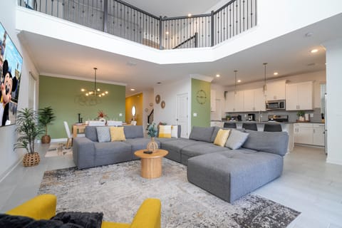 The spacious open living area boasts a modern design with a large, comfortable couch and a big-screen TV, creating the perfect space for relaxation and entertainment. Natural light fills the room with pool views,  truly refreshing and inviting atmosphere.