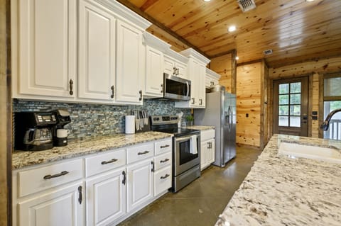 Spacious, fully equipped kitchen featuring stainless steel appliances, granite countertops including a sink, and all the essentials you need to whip up delicious meals. A perfect blend of functionality and style for memorable family gatherings.