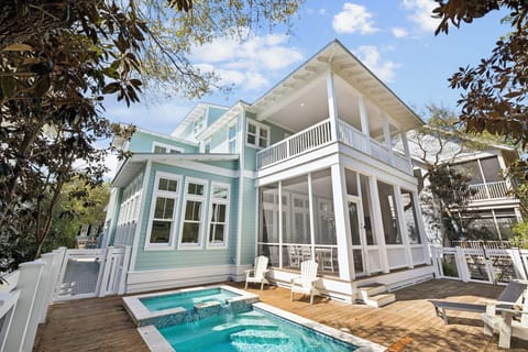 Charming coastal home with private pool and covered porches, nestled among mature trees in a peaceful neighborhood setting.